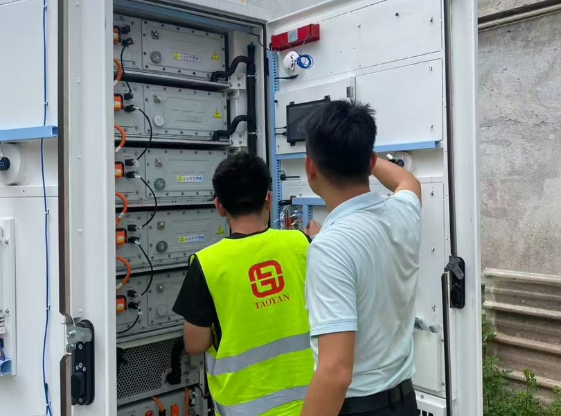 马来西亚 522kWh 储能系统调试 - TAOYAN 技术员在开启的机柜前作业